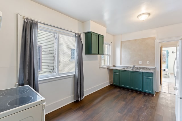 kitchen with stove, dark wood-type flooring, green cabinetry, and sink