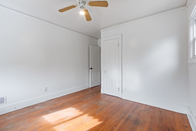 empty room with ceiling fan, crown molding, and wood-type flooring