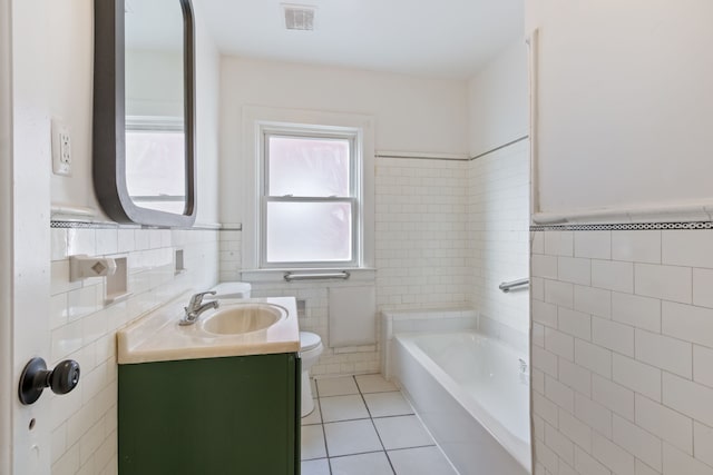 bathroom featuring a tub to relax in, tile patterned floors, vanity, tile walls, and toilet