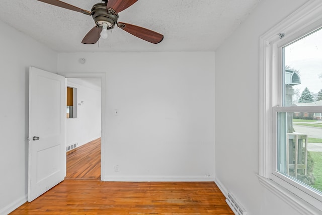 unfurnished room with plenty of natural light, light hardwood / wood-style floors, and a textured ceiling