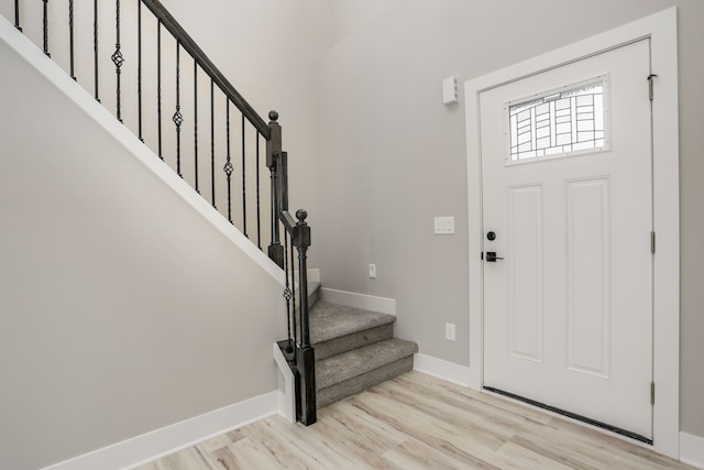 foyer entrance with stairs, baseboards, and wood finished floors