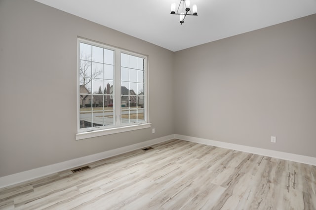 unfurnished room featuring a wealth of natural light, baseboards, visible vents, and a notable chandelier