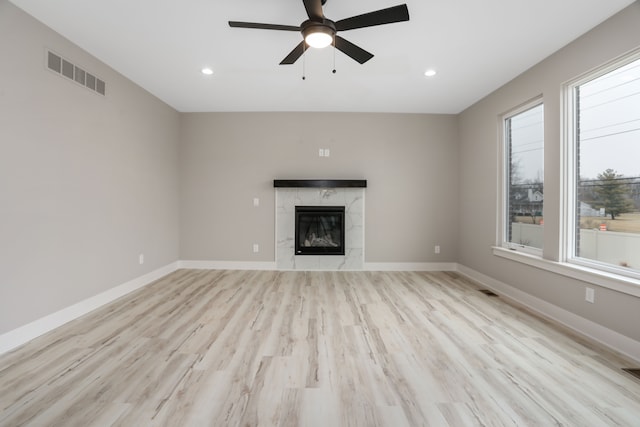 unfurnished living room with baseboards, visible vents, and a high end fireplace