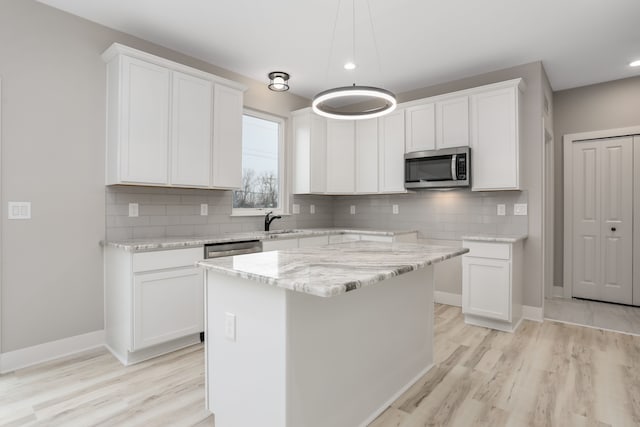 kitchen with stainless steel appliances, tasteful backsplash, light wood-style flooring, white cabinets, and baseboards