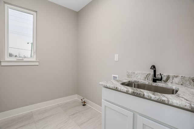 clothes washing area featuring cabinet space, baseboards, hookup for a gas dryer, hookup for a washing machine, and a sink