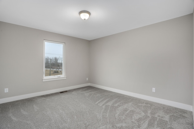 carpeted spare room featuring visible vents and baseboards