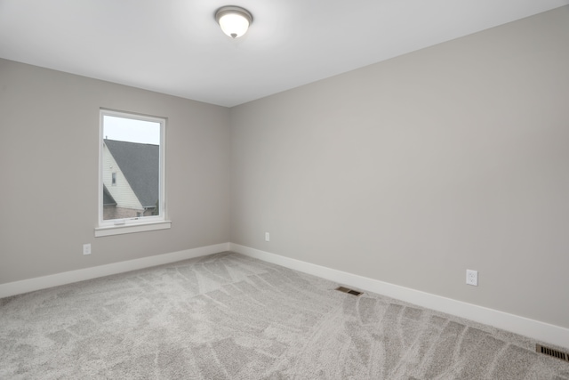 empty room featuring carpet, visible vents, and baseboards