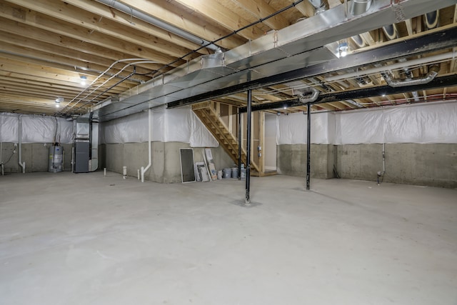 unfinished basement with heating unit, stairway, and gas water heater