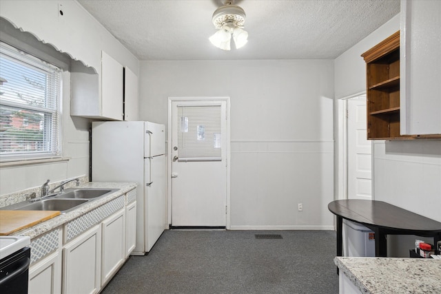 kitchen with white cabinets, white refrigerator, sink, a textured ceiling, and range