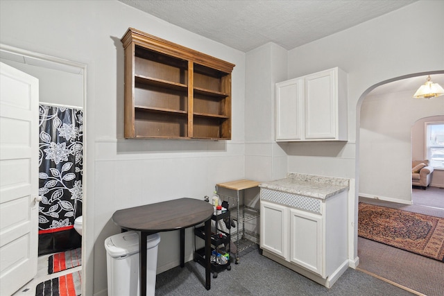 kitchen with white cabinets, a textured ceiling, and dark colored carpet