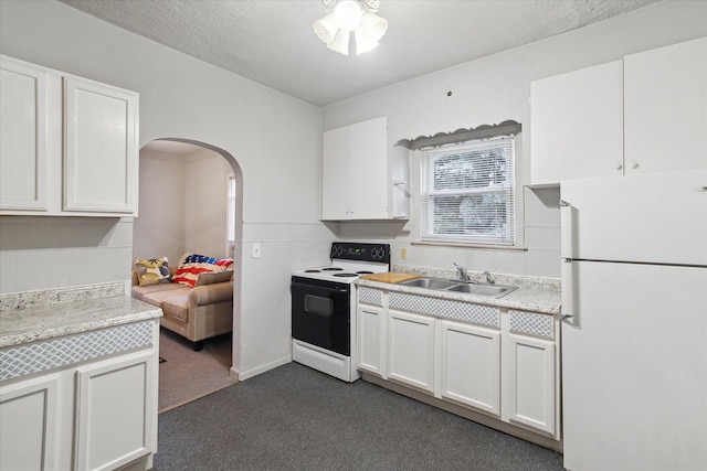 kitchen with white cabinets, dark carpet, white appliances, and sink