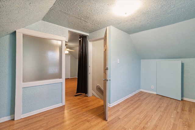 bonus room featuring a textured ceiling, light hardwood / wood-style flooring, ceiling fan, and lofted ceiling