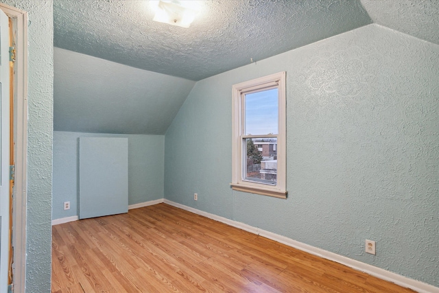 bonus room featuring a textured ceiling, lofted ceiling, and light wood-type flooring