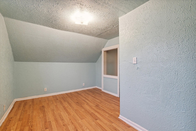 bonus room with wood-type flooring, lofted ceiling, and a textured ceiling