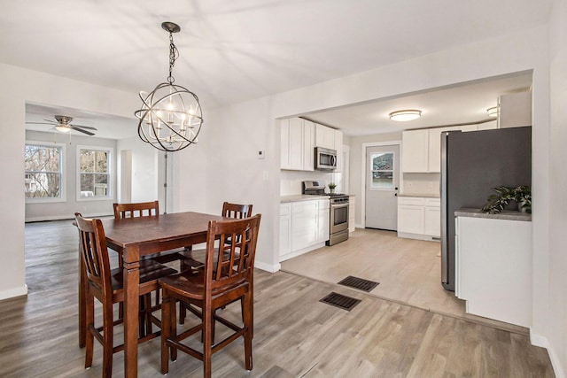 dining area featuring ceiling fan with notable chandelier and light wood-type flooring