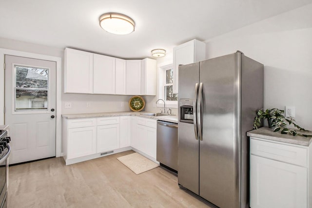 kitchen with sink, stainless steel appliances, light hardwood / wood-style flooring, and white cabinetry