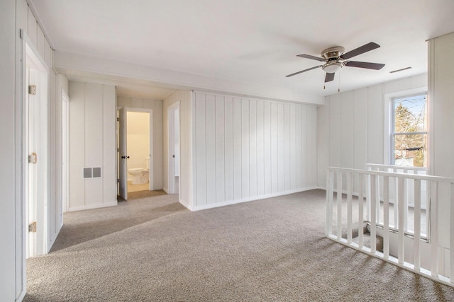 carpeted empty room with wooden walls and ceiling fan