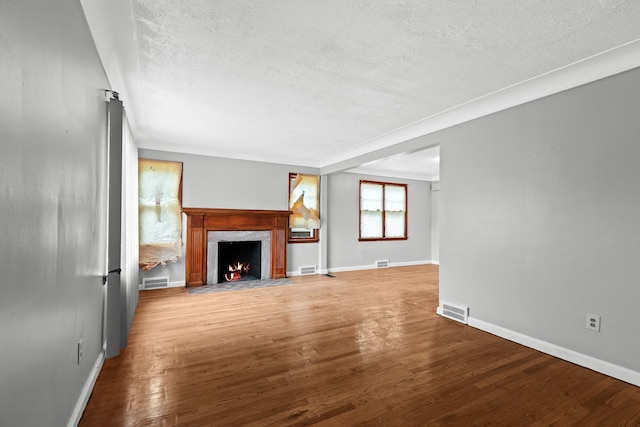 unfurnished living room featuring a premium fireplace, wood-type flooring, and a textured ceiling