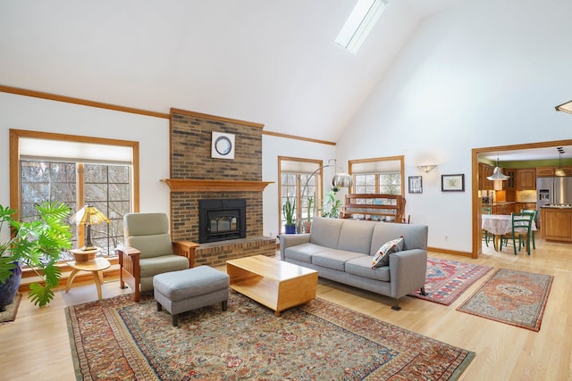 living room with a skylight, a fireplace, a towering ceiling, and light wood-type flooring