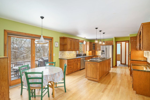 kitchen with tasteful backsplash, stainless steel appliances, sink, a center island, and hanging light fixtures