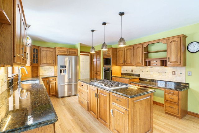 kitchen with a center island, sink, hanging light fixtures, stainless steel appliances, and light wood-type flooring