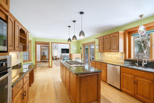 kitchen with pendant lighting, a kitchen island, sink, and stainless steel appliances