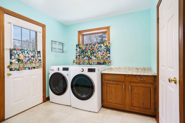 washroom with washer and clothes dryer, cabinets, and light tile patterned floors