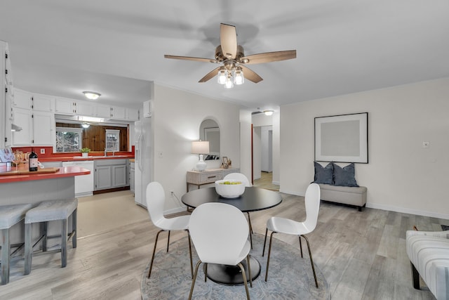 dining area with light hardwood / wood-style floors, ceiling fan, and sink