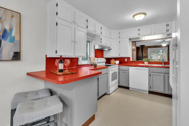 kitchen featuring white cabinets, white appliances, and kitchen peninsula