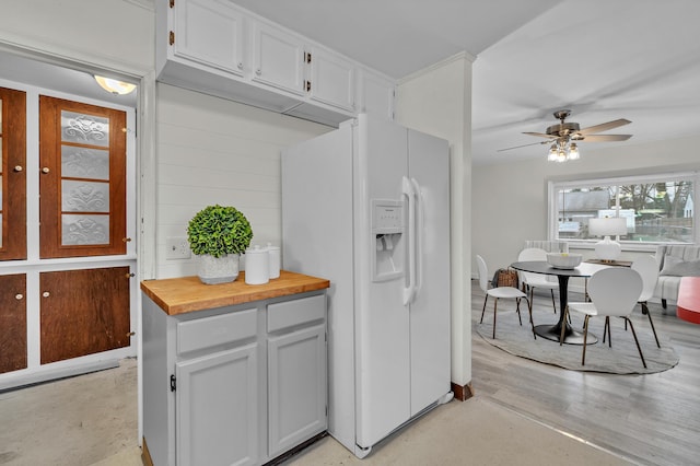 kitchen with ceiling fan, white fridge with ice dispenser, white cabinets, and wooden counters