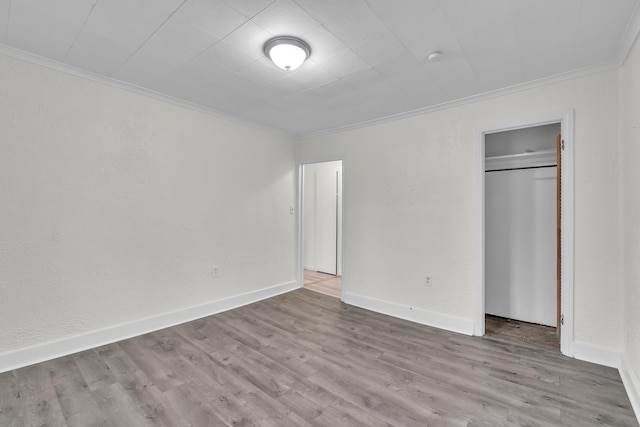 unfurnished bedroom with crown molding, a closet, and light hardwood / wood-style flooring