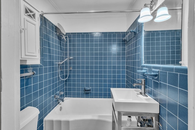 full bathroom with sink, tiled shower / bath combo, toilet, and tile walls