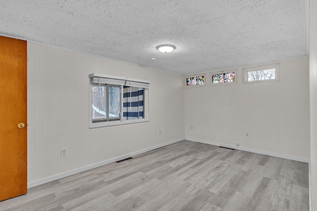 unfurnished room with a textured ceiling and light hardwood / wood-style floors