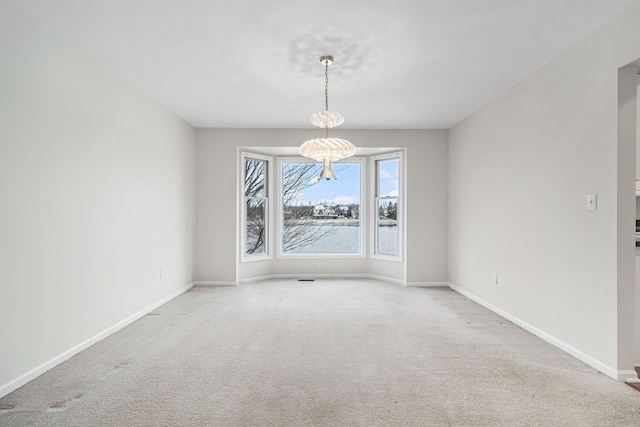 carpeted empty room with a chandelier