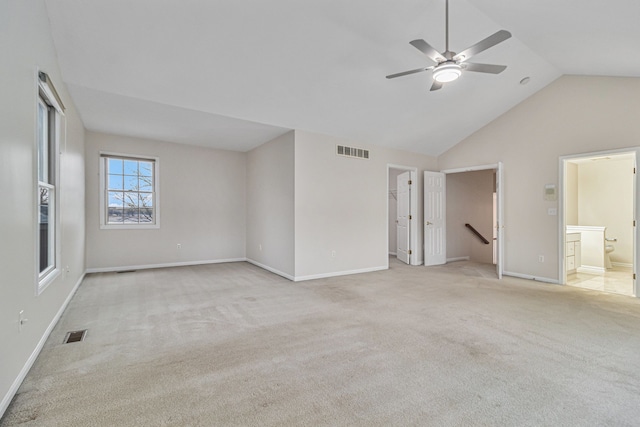 unfurnished bedroom with ceiling fan, ensuite bathroom, lofted ceiling, a walk in closet, and light carpet