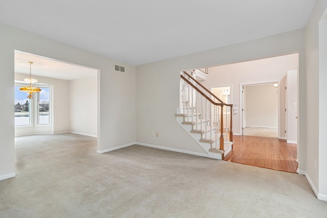 carpeted empty room with an inviting chandelier