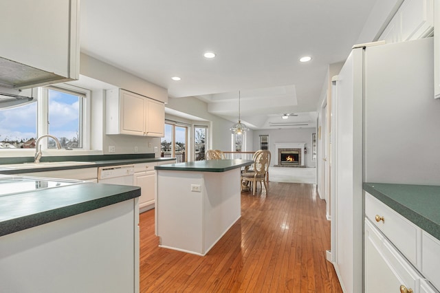 kitchen with white appliances, a wall mounted AC, sink, white cabinets, and light hardwood / wood-style floors