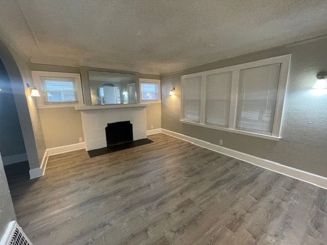 unfurnished living room with plenty of natural light, hardwood / wood-style floors, and a textured ceiling