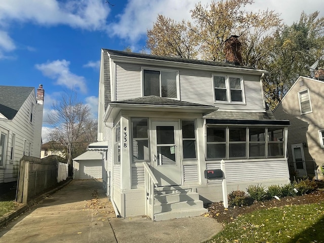 front of property with a sunroom, a garage, and an outbuilding