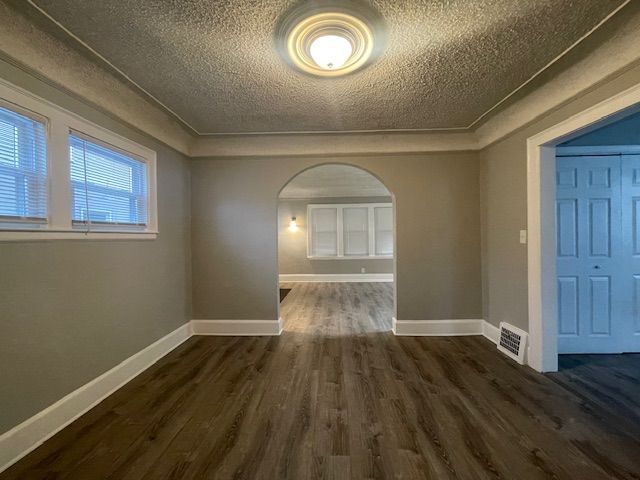 empty room with a textured ceiling and dark wood-type flooring