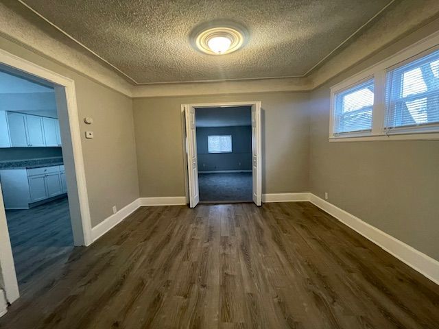 spare room featuring dark hardwood / wood-style floors and a textured ceiling