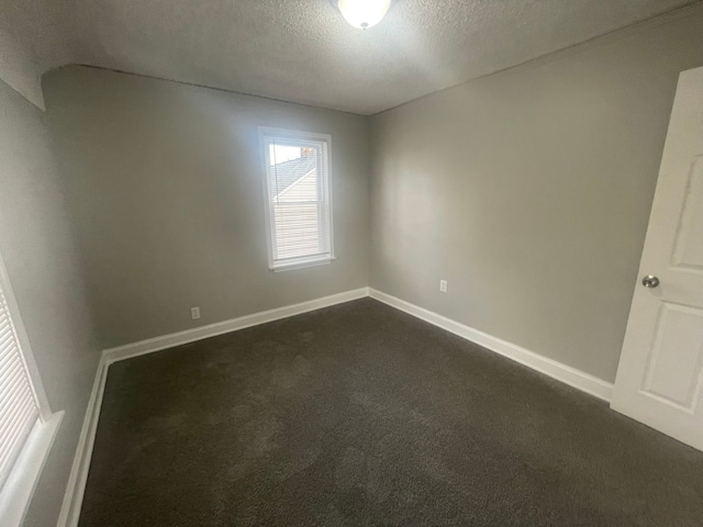 spare room with dark colored carpet and a textured ceiling