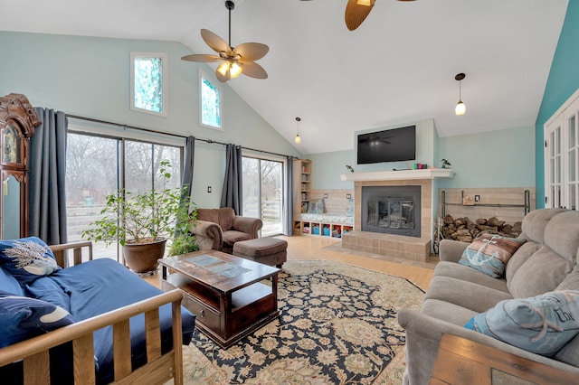 living room with a tiled fireplace, ceiling fan, hardwood / wood-style floors, and high vaulted ceiling