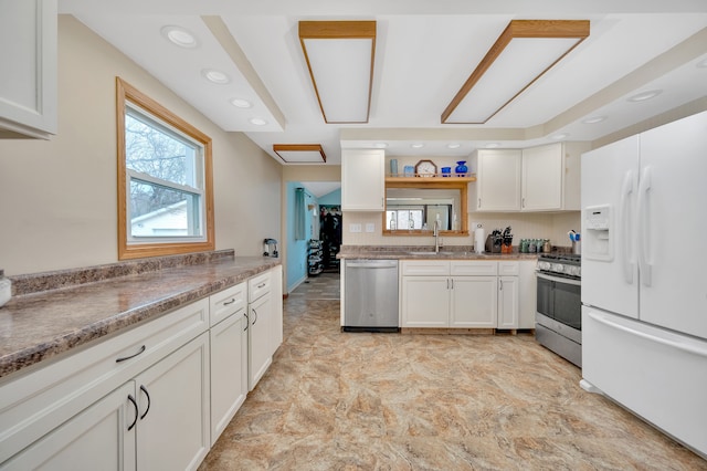 kitchen with light stone counters, white cabinetry, sink, and appliances with stainless steel finishes