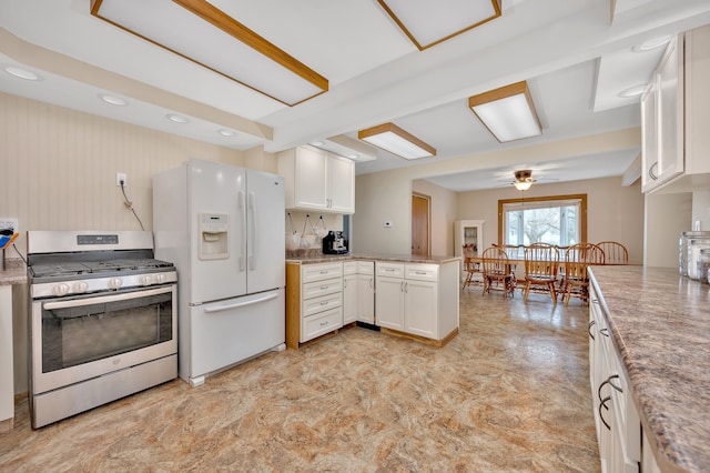 kitchen with white cabinets, kitchen peninsula, white fridge with ice dispenser, and stainless steel range with gas stovetop