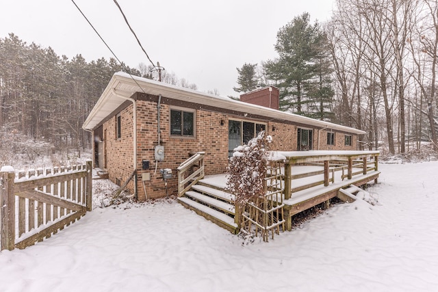 snow covered house with a wooden deck