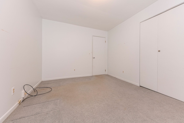 unfurnished bedroom with light carpet and a closet