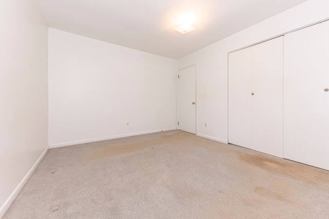 unfurnished bedroom with light carpet and a closet