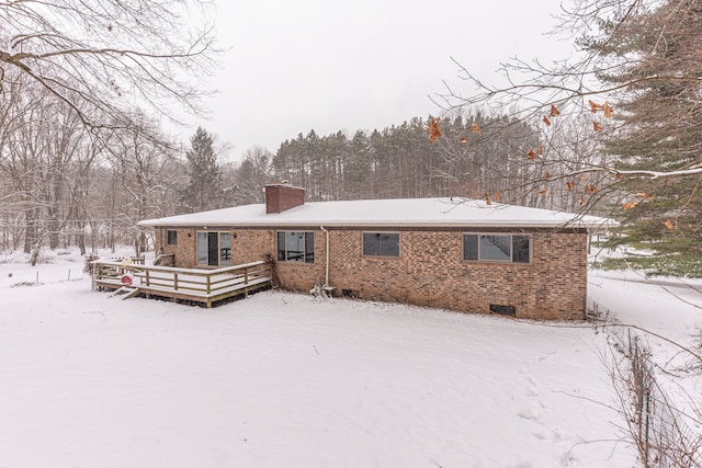 snow covered rear of property with a deck