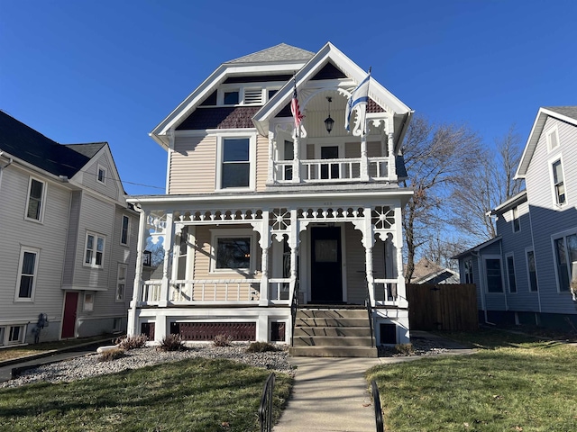 view of front of home with a balcony, covered porch, and a front yard